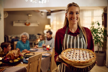Happy mother with Thanksgiving pie looking at camera.