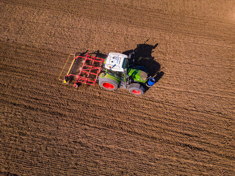 Ein Traktor mit Pflug auf dem Feld von der Seite gesehen mit der Drohne