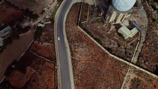 Aerial view of a car driving the countryside road in Dingli, Malta.