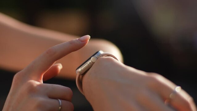 Close-up cropped shot of unrecognizable female runner using sport smart watch, checking running physical activity control outdoors. Closeup of sporty woman looking at smart watch and check heart rate.