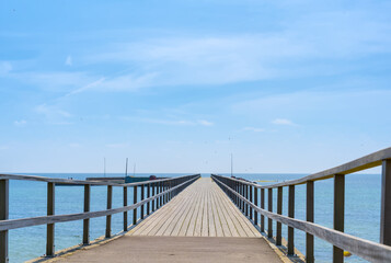 Naklejka premium Wooden walkway to the sea and blue sky with white clouds 