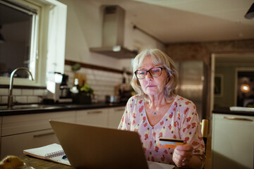 Concerned senior woman paying her bills online from a laptop at home