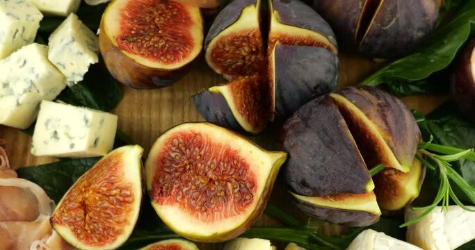 Figs, jamon, spinach leaves and blue cheeses on a wooden board. Snacks set.