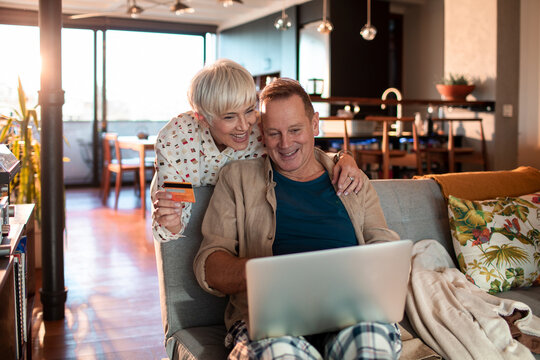 Happy mature couple online shopping from a laptop at home
