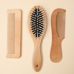 Wooden combs and hair care brush on beige background, top view