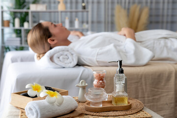 Fototapeta na wymiar Aromatherapy massage on daylight ambiance or spa salon composition setup with focus decor and spa accessories on blur woman enjoying blissful aroma spa massage in resort or hotel background. Quiescent