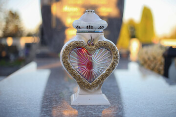 Close up of Votive candles lantern on the grave in Slovak Catholic cemetery during day. Autumn scene. All Hallows eve. Memorial to the deceased. Solemnity of All Saints. 1st November, All Saints' Day