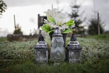 Close up of Votive candles lantern on the grave in Slovak Catholic cemetery during day. Autumn scene. All Hallows eve. Memorial to the deceased. Solemnity of All Saints. 1st November, All Saints' Day