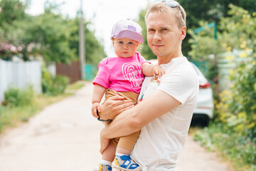 Caucasian baby child girl in the arms of a young father in summer outdoor