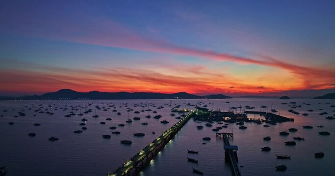 .aerial view colorful sunrise above Chalong pier..4K vdo of Majestic sunrise landscape Amazing light of .nature cloudscape sky above mountain range. .boats yacht in Chalong marina gulf background.