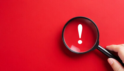 Magnifying glass and exclamation mark on red background - obrazy, fototapety, plakaty