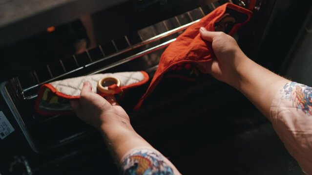 Woman hands taking pie omelette out of oven using oven mitts. Close up.