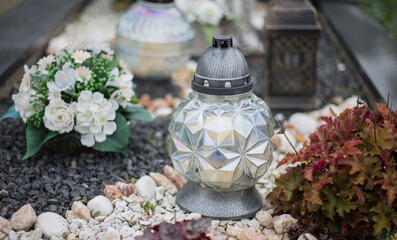 Close up of Votive candles lantern on the grave in Slovak Catholic cemetery during day. Autumn scene. All Hallows eve. Memorial to the deceased. Solemnity of All Saints. 1st November, All Saints' Day