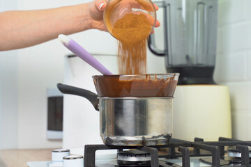 The pastry chef pours cinnamon into melted chocolate.