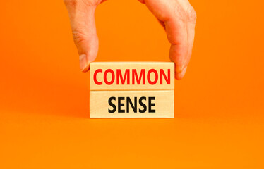 Common sense symbol. Concept words Common sense on beautiful wooden block. Beautiful orange table orange background. Businessman hand. Business, motivational common sense concept. Copy space.