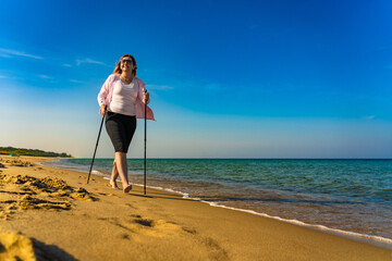 Nordic walking - beautiful woman exercising on beach
