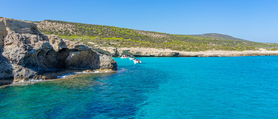 blue lagoon in the Aphrodite bathing area with caves in the rocks next to the turquoise sea. ...