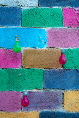 wall with bricks painted in different colors with incandescent lamps painted in different colors.