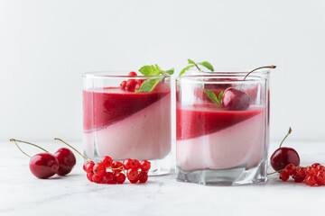 Delicious Italian dessert panna cotta with red berry sauce, fresh cherries, currant and mint leaves...
