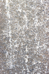 Vertical photo of an old, gray, concrete wall damaged by time.
