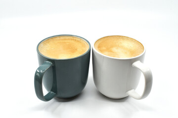 Two mugs of hot coffee in contrasting coloured mugs isolated on a plain white background