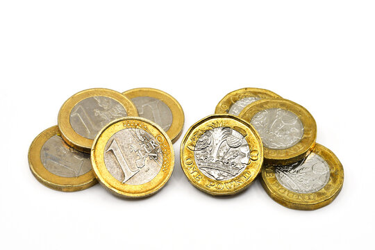 One Euro coins and British one pound coins isolated on a plain white background. Copy space.