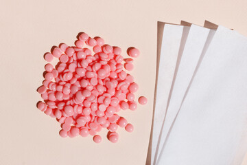 Beautiful pink depilatory wax granules and depilatory strips on a pastel background. Epilation, depilation, unwanted hair removal