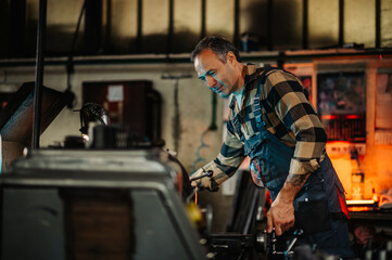 Fototapeta na wymiar A metallurgy machinist operating a metal turning machine in a workshop.