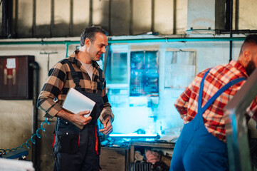 A supervisor monitoring the work of a new employee in a factory.