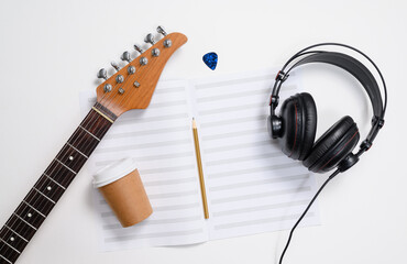 Notebook for guitar and headphones on a white background. View from above. Music lesson concept