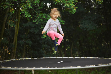 Child jumping on a trampoline in the evening garden in Denmark
