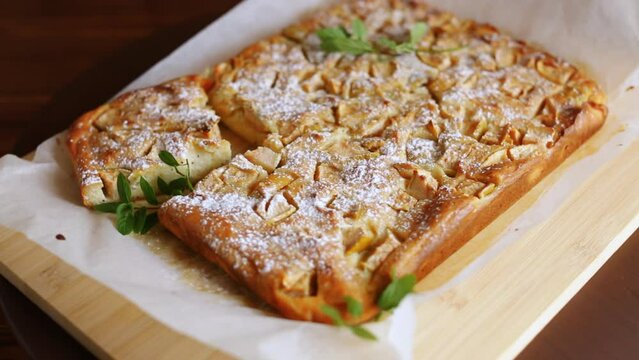 prepared curd semolina pie with quince inside and covered with powdered sugar on a wooden board.