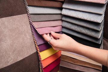 A young girl is holding a fabric catalog for choosing fabric for upholstered furniture, the girl...