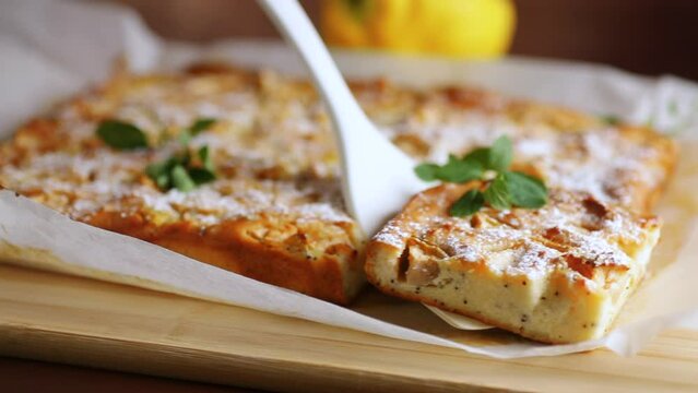 prepared curd semolina pie with quince inside and covered with powdered sugar on a wooden board.
