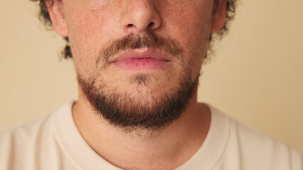 Fototapeta premium Detailed close-up shot of man's face in studio on beige background