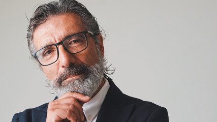 Close up, businessman hand props chin turns his head and looks at the camera, on gray background