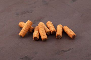 Waffle tubes with chocolate filling on brown background. Crispy wafer rolls