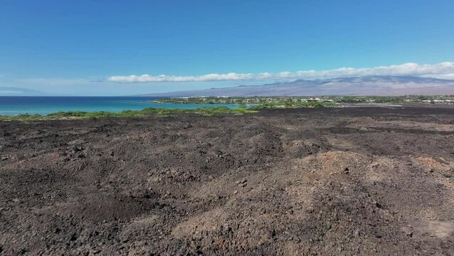 Aerial volcanic lava flow Kona Hawaii ocean pull. Big Island Kilauea and Maunaloa volcanos are the most active on earth. Economy is tourism. Tropical beach, nature, rainforest, desert recreation.