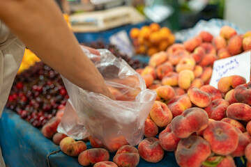 Close-up view of Woman buy fresh ripe peaches at farmer market