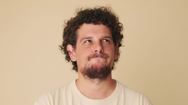 Close up, man thinks over his problem, remembering something isolated on beige background 
