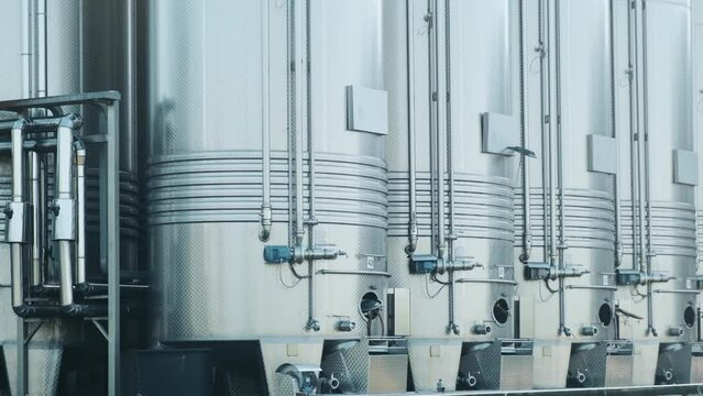 Stainless steel storage tanks for wine fermentation and maturation in modern winery factory production. Close up. Industrial and technology background