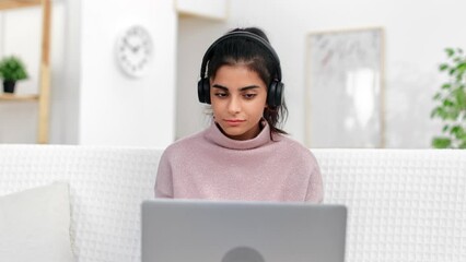 Smart Asian woman talking online video call in headphones use laptop working remotely communication