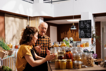 Father and daughter in environmentally responsible zero waste store interested in buying food with...