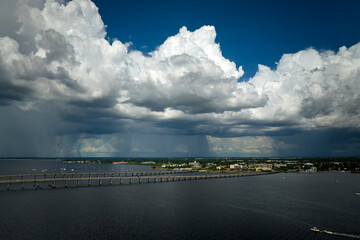 Stormy clouds forming from evaporating humidity of ocean water before thunderstorm over traffic bridge connecting Punta Gorda and Port Charlotte over Peace River. Bad weather conditions for driving