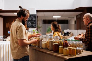 Man in environmentally responsible zero waste store interested in buying food with high nutritional value. Client looking for pantry staples in reusable packaging in local grocery shop