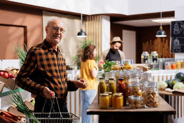 Portrait of elderly man looking for fresh vegetables in eco friendly zero waste store. Aged...