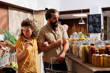 Green living couple shopping in zero waste supermarket, looking for organic food. Vegan customers...