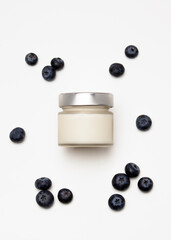 scented candle in a glass jar with blueberries on a white background