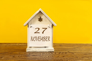 Calendar for November 27: the name November in English, the numbers 27 on a decorative house on a...