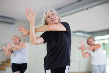 Fototapeta na wymiar Group of three mature women performing modern dance in exercise room.